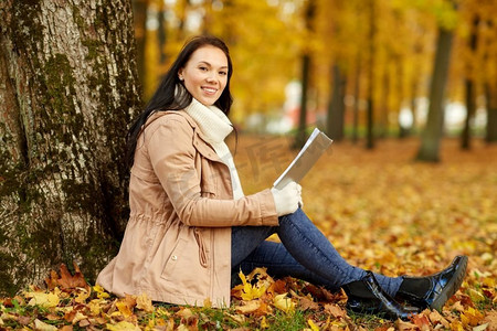 季节，技术和人的概念—年轻女子在秋季公园读书。秋天公园的女人读书