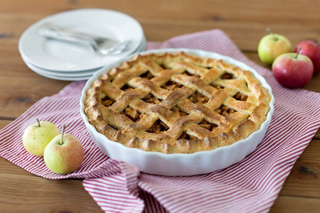食物，烹饪和烘焙概念—苹果派和厨房毛巾在木桌上。苹果派在烤模具在木桌上