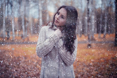 冬季肖像的年轻女孩与雪花在空中