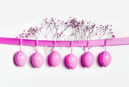 霓虹摄影照片_霓虹灯粉红色复活节彩蛋悬挂在丝带在白色墙壁背景
