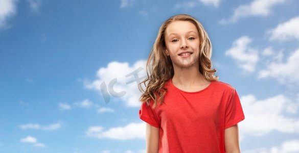 人们概念—微笑的少女有长头发在红色t恤在蓝天和云彩背景微笑的少女在红色T恤在天空