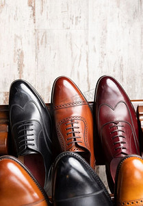 黑色和棕色全粒面皮鞋在男鞋精品店的木质陈列中..男士鞋类精品店