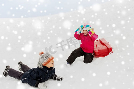 圣诞节小朋友摄影照片_童年、雪橇和季节概念-冬天带着雪橇下雪山的快乐小朋友。冬天带着雪橇下山的快乐小朋友