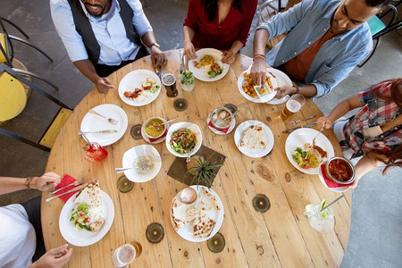 休闲，美食和人的概念—一群快乐的国际朋友在餐厅的餐桌上用餐。国际朋友在餐馆吃饭