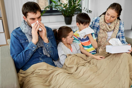 家庭、健康问题和人们的观念—生病的父亲、母亲、女儿和儿子在家擤鼻涕。家里有孩子患流感的家庭
