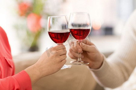 庆祝，饮料和酒精概念—夫妇的手叮当红葡萄酒杯。夫妇的手碰红葡萄酒杯