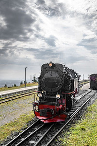 黑色机车与红色的颜色驾驶在一条铁路轨道在多云的天空