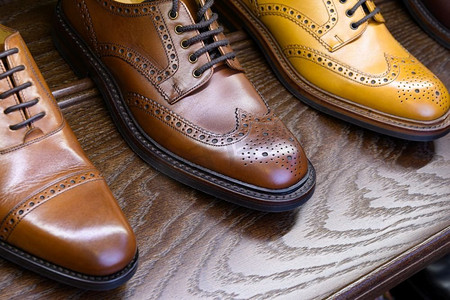 字体排版男鞋摄影照片_棕色全粒面皮鞋在木制显示在男鞋精品店。男士鞋业精品店