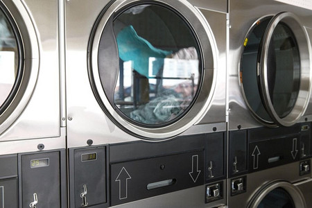 自助洗衣设施概念—洗衣机内的衣服在自助洗衣店。洗衣店内装有衣物的洗衣机