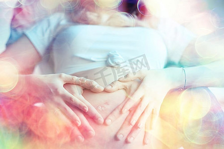 怀孕概念分娩和爱/男人和女人，大肚子，手在心脏的形状，怀孕和爱的象征