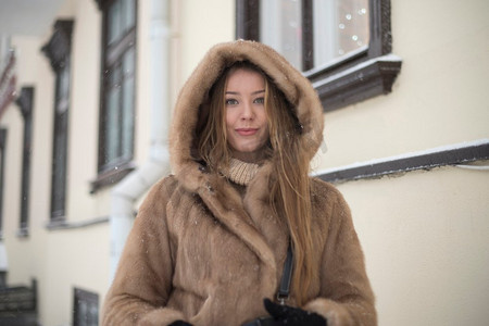 一个女孩在一个毛皮大衣走在城市