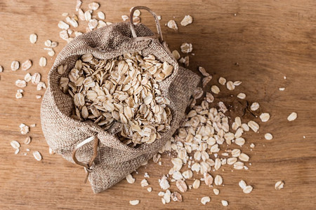 节食。燕麦谷物在粗麻布袋在木表面，顶部，视图。降胆固醇、保护心脏的健康食品。