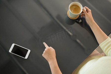 科技与人的概念-女性使用黑色互动面板喝咖啡的特写。喝咖啡的女人使用黑色互动面板