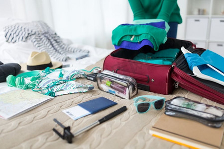 旅游，人和行李概念—快乐的年轻女子包装旅行袋在家里或酒店房间。妇女在家里或酒店房间打包旅行袋