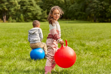 童年，休闲和人的概念—快乐的孩子在公园里跳。快乐的孩子们弹跳在跳球在公园