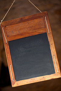 黑色招牌摄影照片_传统的干净的、普通的或空白的黑板或黑板菜单招牌，悬挂在餐馆里