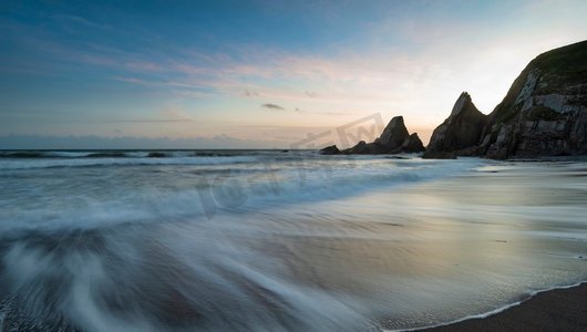 锯齿状边框摄影照片_英格兰德文郡韦斯特科姆海滩美丽的日落景观，海滩上有锯齿状的岩石和令人惊叹的云层
