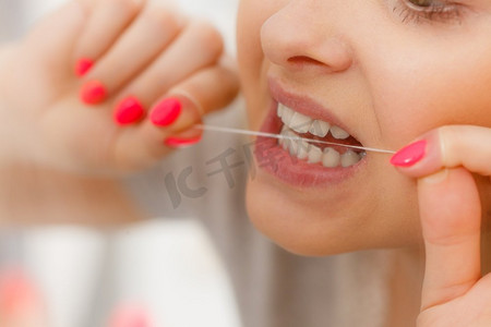 日常口腔卫生，牙科概念。妇女清洁她的牙齿使用牙线。妇女清洁她的牙齿使用牙线