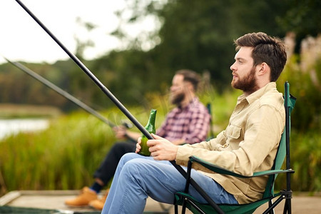 休闲和人的概念—朋友在湖边钓鱼和喝啤酒。朋友钓鱼和喝啤酒在湖