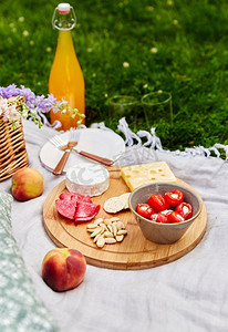 野餐毯摄影照片_休闲和饮料概念-在草地上的野餐毯子上近距离放置食物、饮料和篮子。草地上野餐毯上的食物、饮料和篮子