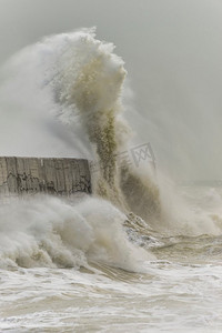 在英国海岸的纽黑文的暴风雨中，惊人的海浪撞击在港口墙壁上