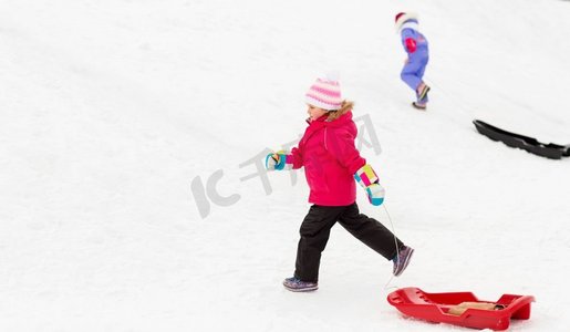 童年，雪橇和季节概念—快乐的小女孩雪橇爬雪山在冬天。小女孩与雪橇在雪山在冬天