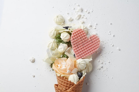 美丽的花在冰淇淋甜筒与蛋白和华夫饼心脏在白色背景。一种花的组合华夫饼