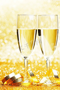 金色猪蹄子摄影照片_两杯香槟与蝴蝶结在金色背景