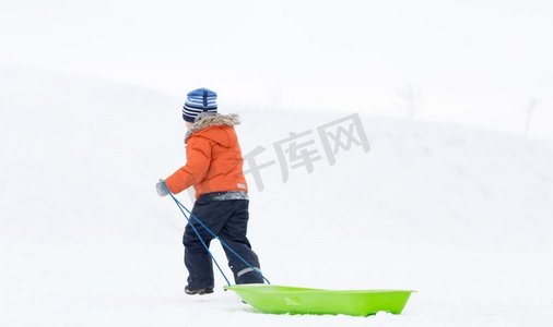 童年，雪橇和季节概念—男孩与雪橇爬雪山在冬天。小男孩与雪橇爬雪山在冬天
