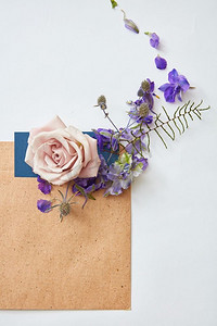 婚礼邀请函、工艺信封、白色背景鲜花。俯瞰。平铺，俯视。带信封的鲜花