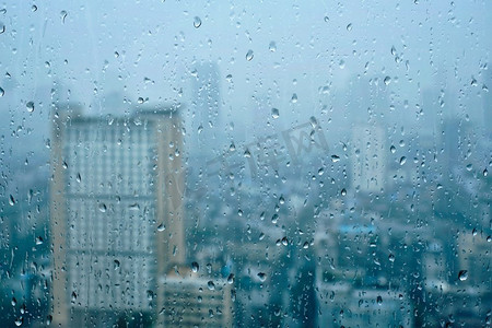 雨滴雨水摄影照片_雨水滴在窗口玻璃纹理与摩天大楼在背景。雨点落在窗户上