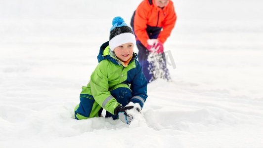 童年、休闲和季节概念-快乐的小孩子们穿着冬衣在户外玩雪。冬天快乐的小孩子们在户外玩耍