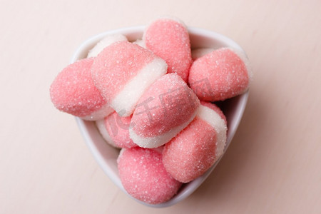甜食糖果。粉红色果冻或棉花糖与糖在白色碗在木桌