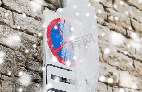 季节、交通和冬天的概念--结冰不让路牌越过墙。墙上覆盖着冰的禁止停车的路牌