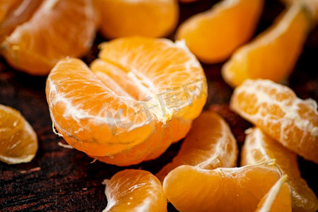 食品背景黄色摄影照片_去皮的橘子。在黑暗的背景下。高质量的照片。去皮的橘子。在黑暗的背景下。