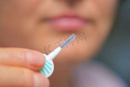 医疗清洁摄影照片_妇女用齿间刷清洁她的牙齿