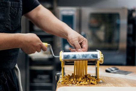 男厨师用机械切碎新鲜的意大利面面团。高分辨率照片。男厨师用机械切碎新鲜的意大利面面团。高品质的照片