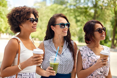 休闲、人情、友谊的概念—快乐的女人或朋友带外卖饮料夏日公园。快乐的女人或朋友与饮料在夏季公园