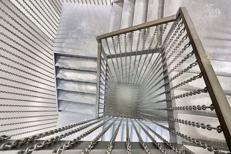 螺旋摄影照片_在金属螺旋楼梯和金属台阶上从上到下观看。螺旋金属楼梯