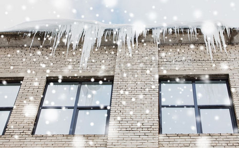 季节、住房和冬季概念-建筑或居住房屋立面上的冰柱。建筑物或起居室正面的冰柱