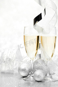 玻璃香槟和圣诞装饰球在闪光背景