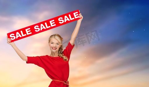 购物和促进概念—微笑的妇女穿着与红色销售标志在天空背景穿着红色销售标志的女人