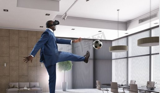 一个黑人在房间里戴着虚拟现实头盔踢足球。黑人和虚拟现实足球游戏