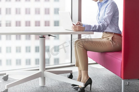 低层摄影照片_坐在办公室里使用笔记本电脑的低层女商人