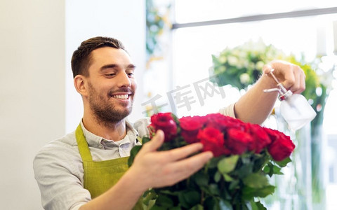 小企业，销售和花艺概念—花商或卖方设置红玫瑰在花店。在花店里摆放红玫瑰的花店或售货员