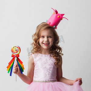 美丽的小糖果公主女孩在冠拿着大棒棒糖和微笑。糖果公主女孩与棒棒糖
