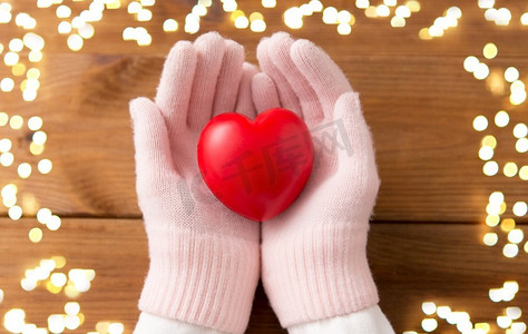 冬天,情人节和圣诞节的概念 — 双手戴着淡粉色羊毛手套,在木板背景上