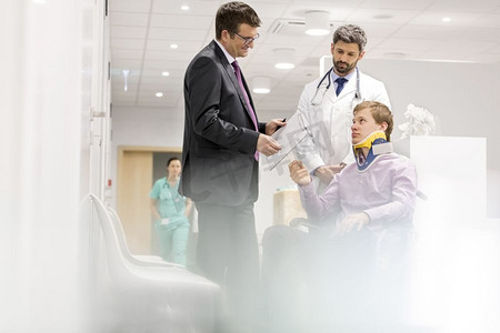 成熟的专科医生在医院轮椅上与病人交谈