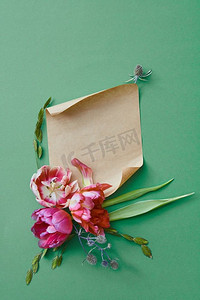 花卉文字摄影照片_一束紫色的花在绿色背景与一张牛皮纸的文字，平躺。鲜花作为背景