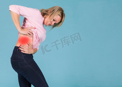 压力妇女遭受下背部疼痛蓝色背景